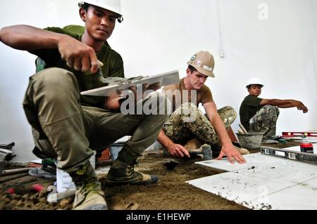 U.S. Marine Equipment Operator Constructionman Aaron Lynch, Center, legt Bodenfliese mit kambodschanische Soldaten während einer technischen Stockfoto