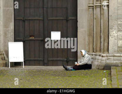 Frau betteln an eine Kirchentür in Köln Stockfoto