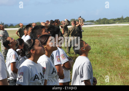 Tinian Schülerinnen und Schüler mit der Schule? s junior ROTC-Programm Uhr wie ein US-Marinekorps F/A - 18D Hornet-Flugzeug fliegt Ov Stockfoto