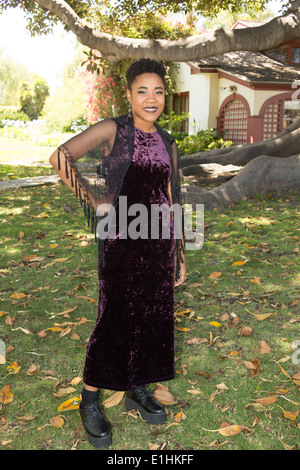 Outdoor-Porträt einer schwarzen jungen Frau in einem lila Samtkleid Stockfoto