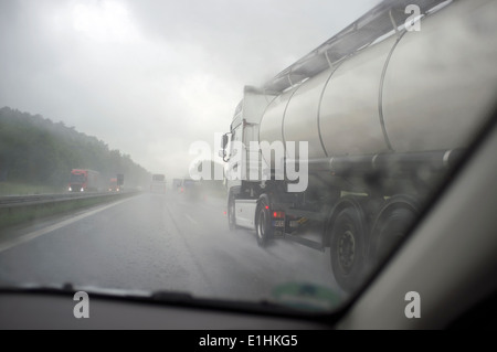 Lastwagen fahren durch Regen auf der Autobahn A8 Richtung Norden in Richtung München, Bayern, Deutschland. Stockfoto