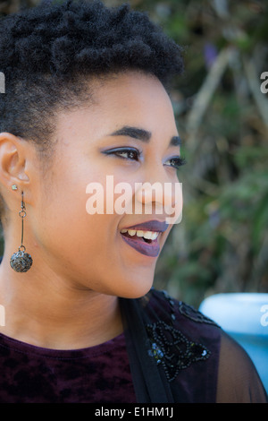 Outdoor-Porträt einer schwarzen jungen Frau in einem lila Samtkleid Stockfoto
