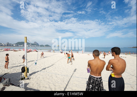 RIO DE JANEIRO, Brasilien - Januar 2011: Junge brasilianische Männer beobachten ein Spiel der Footvolley, ein Sport von Fußball und Volleyball. Stockfoto