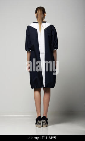 Rückansicht des trendigen Chichi Frau in weiß-schwarz-Kontrast Regenmantel. Vogue Stockfoto