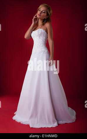 Blonde Braut Mode-Modell in langen weißen Brautkleid auf rotem Hintergrund - Serie von Fotos Stockfoto