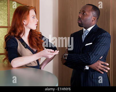 Unternehmer - Redhair sommersprossige junge Geschäftsfrau und schwarze Geschäftsmann stehend - Serie von Fotos Stockfoto