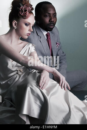 Paar der Mode Modelle sitzen - stilvolle schwarze amerikanische Mann und Rothaarige modische Frau Stockfoto