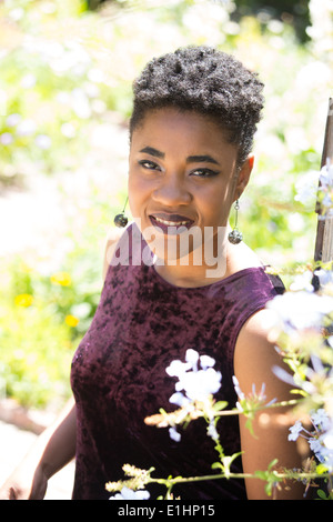 Porträt einer jungen schwarzen Frau mit kurzen Haaren in einem Garten Stockfoto