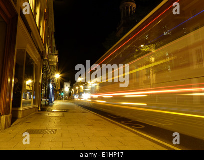 Langzeitbelichtung ein Bus in Richtung entlang einer Hauptstraße nachts verlassen Lichtspuren Stockfoto