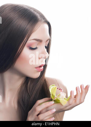 Junge schöne Frau Gesicht mit frischen Orchidee Blume close-up Portrait. Saubere, gesunde Haut Stockfoto