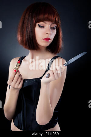 Schönes Mädchen in rotem Haarperücke aufstellen auf Make - spiegelt auf Tabelle Messer