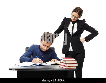 Studioaufnahme des Lehrers stehen neben Schülers Schreibtisch mit Hand auf Taille, Überwachung, ihn isoliert auf weißem Hintergrund Stockfoto