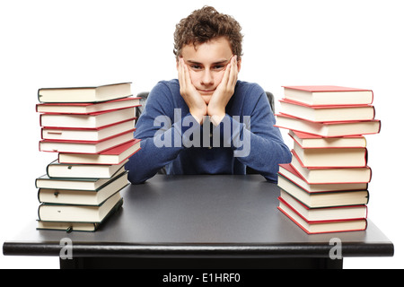 Studioaufnahme des hoffnungslosen Schüler mit Gesicht in Händen sitzt an seinem Schreibtisch zwischen zwei Haufen Bücher, isoliert Stockfoto