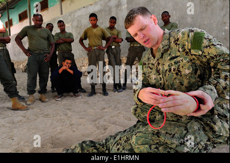 US Navy Chief Master-at-Arms Neil McLean, eine maritime zivile Angelegenheiten und Sicherheit Training Ausbilder demonstriert Handschellen Stockfoto