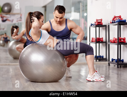 Persönlicher Trainer hilft Frau tun abs Crunches mit Gymnastikball Stockfoto