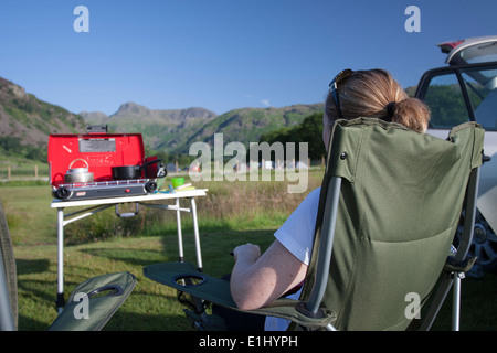 Junge Frau (30-35) auf Campingstuhl auf Campingplatz in Cumbria Stockfoto