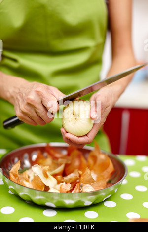 Nahaufnahme von den Händen einer jungen Frau schälen und schneiden die Zwiebel in der Küche Stockfoto