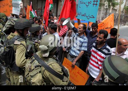 Hebron, Westjordanland, Palästinensische Gebiete. 5. Juni 2014. Palästinensische Demonstranten halten ein Schild vor israelischen Truppen während einer Protestaktion in Solidarität mit den Gefangenen in den Hungerstreik getreten, in der West Bank von Hebron 5. Juni 2014. Rund 120 Palästinenser ohne Gerichtsverfahren in Israel inhaftiert wurden auf einen unbefristeten Hungerstreik, Essen nur Salz und Wasser, seit dem 24. April, fordern ein Ende der so genannten '' Verwaltungshaft Credit: Mamoun Wazwaz/APA Images/ZUMAPRESS.com/Alamy Live News Stockfoto