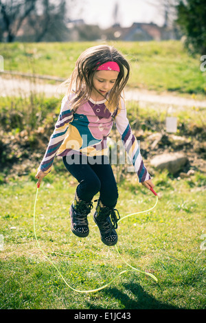 Kleines Mädchen Springseil im Garten Stockfoto