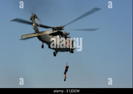 Ein US-Marine MH-60 s Knighthawk Hubschrauber zugewiesen, Hubschrauber Meer bekämpfen Squadron (HSC) 8 gewinnt einen Seemann während eine explosive Stockfoto