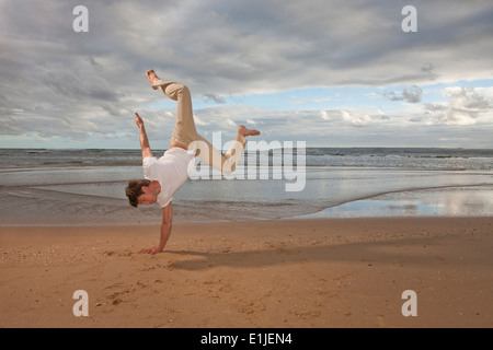 Junger Mann tun Handstand am Strand Stockfoto