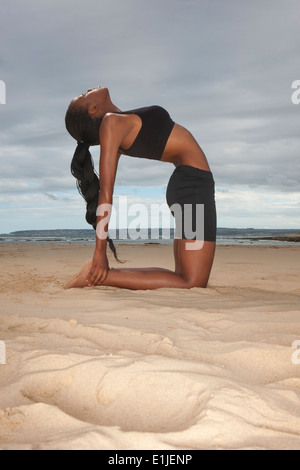 Junge Frau praktizieren Yoga am Strand Stockfoto