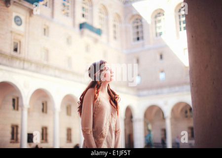 Junge Frau blickte im historischen Innenhof Stockfoto