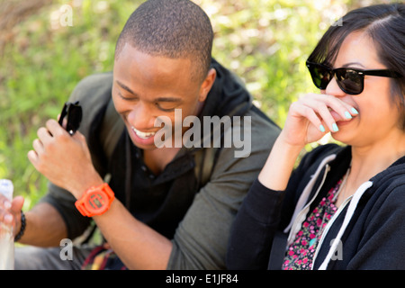 Junges Paar sitzt im Park zu lachen Stockfoto