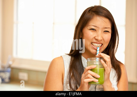 Junge Frau trinken grünen smoothie Stockfoto