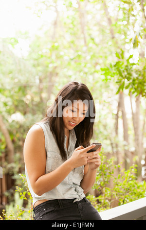 Junge Frau mit Smartphone auf Veranda Stockfoto