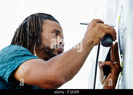 Nahaufnahme eines männlichen Afroamerikaner Airbrush Künstler Malerei Wandbild Stockfoto