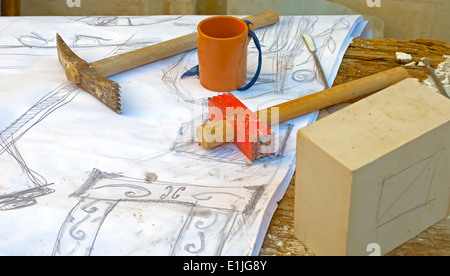 Hämmer und Meißel, um den Stein ruht auf einer Bleistiftskizze schnitzen Stockfoto