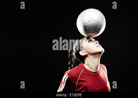 Junge Frau balancieren Fußball auf Stirn Stockfoto