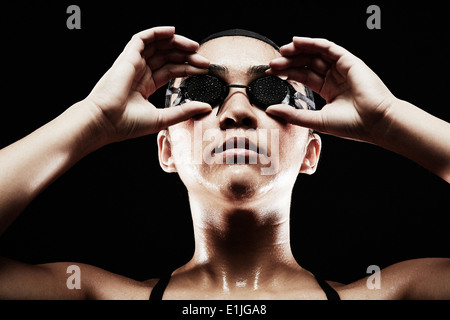 Junge Frau, die Schwimmbrille aufsetzen Stockfoto