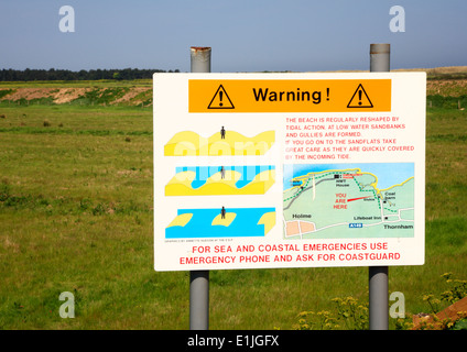 Ein Warnschild gegen ankommenden Gezeiten an Dornweiler, Norfolk, England, Vereinigtes Königreich. Stockfoto