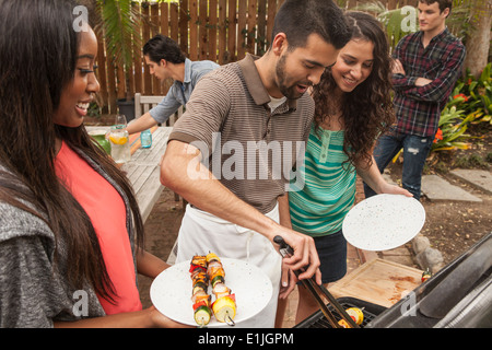 Freunde an Tisch Grill Essen teilen Stockfoto