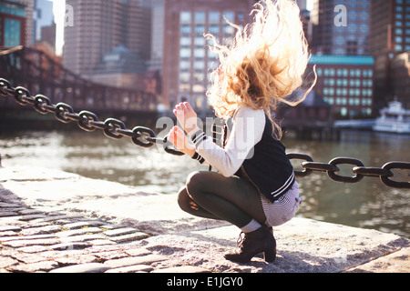 Junge Frau hocken und Haar streichen Stockfoto