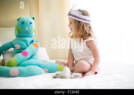 Junges Mädchen Tee mit Kuscheltier auf Bett teilen Stockfoto