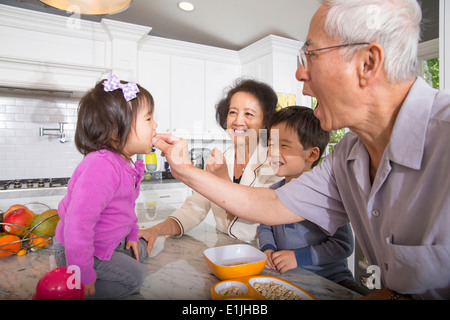 Großvater Fütterung Snack Kleinkind Enkelin in Küche Stockfoto