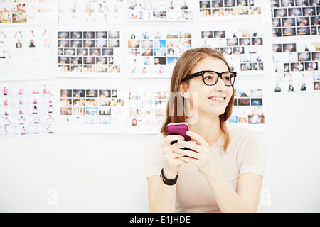 Junge Frau mit Handy im Kreativstudio Stockfoto