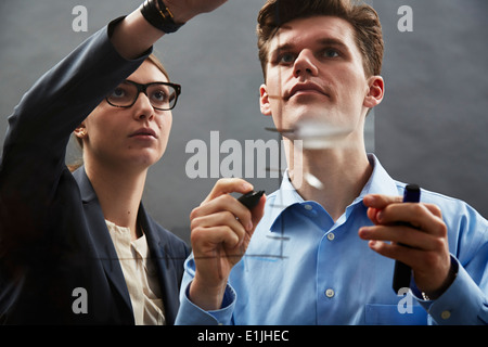 Geschäftskollegen zeichnen von Graphen auf Glas Stockfoto