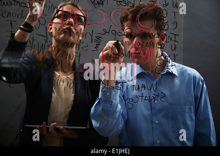 Geschäftskollegen schreiben auf Glas Stockfoto