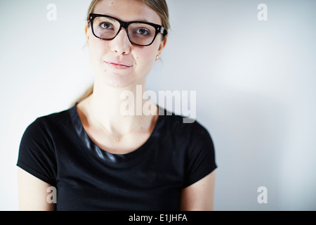 Junge Frau trägt Brille und schwarzes Oberteil, Studio gedreht Stockfoto
