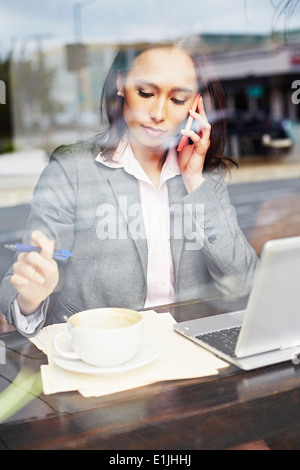 Junge weibliche Unternehmerin auf Smartphone im café Stockfoto