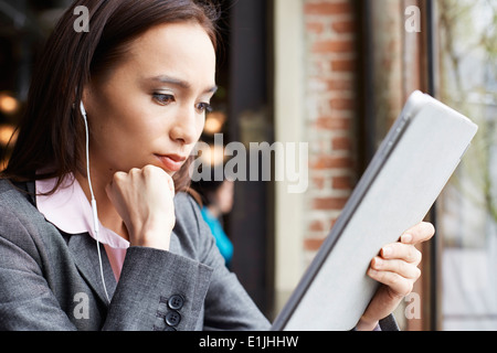 Junge weibliche Unternehmerin mit Kopfhörern Schreibarbeit im Café lesen Stockfoto