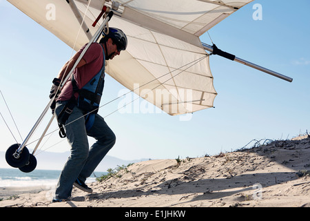 Mann trägt Hängegleiter am Strand Stockfoto