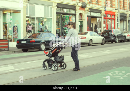 Junge Mutter schieben Kinderwagen über Brunswick Street Fitzroy Melbourne Australien Stockfoto