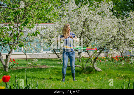 Mädchen drehen Hula-Hoop zwischen blühenden Kirschbäume Baum, eine perfekte Taille zu haben Stockfoto