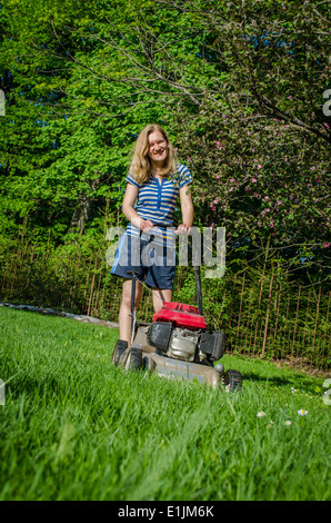 lächelnde Land Arbeit Frau und Kraftstoff Rasen Schneidemaschine im Garten Saisonarbeit Stockfoto