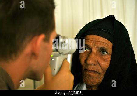 Major Marcus Neuffer, 455. Expeditionary Praxisgemeinschaft Augenarzt verwaltet eine Augenuntersuchung eines afghanischen Patienten in der Kor Stockfoto